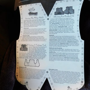 May include: A close-up of a white and black printed instruction sheet for altering and sewing a vintage vest. The instructions include diagrams and text in English, French, Spanish, Italian, and Portuguese. The text includes instructions for sewing the whip stitch, lining the vest, altering the shoulder fit, altering the vest length, altering the vest width, and adding a lining.