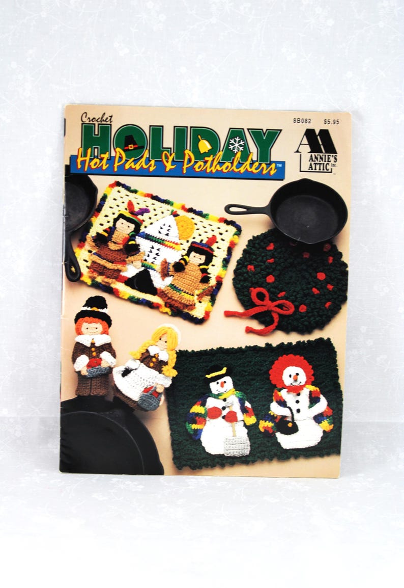May include: Crochet Holiday Hot Pads & Potholders pattern book featuring a variety of designs including a snowman, pilgrims, and a Native American family. The book cover is red, white, and blue with a snowflake and a bell.