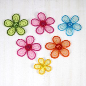 May include: Six colorful fabric flowers with beaded centers. The flowers are in shades of green, pink, orange, blue, and yellow.