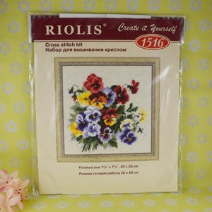 May include: Cross stitch kit with a colorful floral design featuring a bouquet of pansies. The kit includes a pre-printed Aida cloth, embroidery floss, and instructions. The finished size is 7 3/4 inches by 7 inches, or 20 centimeters by 20 centimeters.