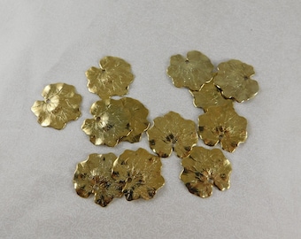 May include: Ten gold-colored metal leaf-shaped embellishments with a hole in the center. The leaves have a textured surface and are arranged in a random pattern.