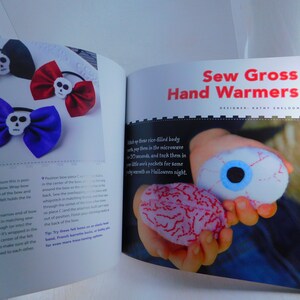 May include: A book titled "Sew Gross Hand Warmers" with a photo of a child holding two hand warmers shaped like an eyeball and a brain. The book is open to a page with instructions on how to make the hand warmers.