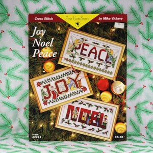 Ulotka do haftu krzyżykowego „Joy Noel Peace” z rocznika 1995, projektant Mike Vickery, Just Cross Stitch nr 2211, trzy szczegółowe wzory świąteczne
