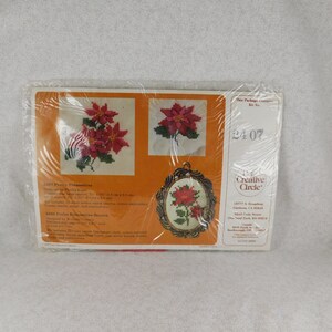 May include: A Creative Circle cross-stitch kit featuring a poinsettia design. The kit includes red, green, and white embroidery floss, a needle, and instructions. The kit number is 3407.