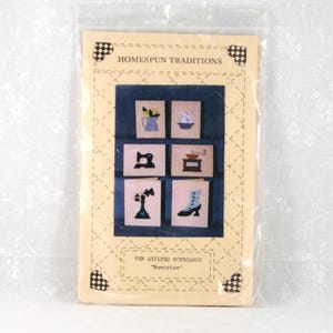 May include: A package of pen quilted notecards titled "Memories" featuring six small embroidered images of a vase, bowl, sewing machine, coffee grinder, telephone, and boot. The package is sealed in clear plastic and has the text "Homespun Traditions".
