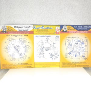 May include: Three vintage Aunt Martha's Hot Iron Transfers packages. The packages feature designs for embroidery, fabric painting, and quilting. The titles are "Fruit 'N Veggie Pup", "Hey Diddle Diddle", and "Miss Kitty Kot".