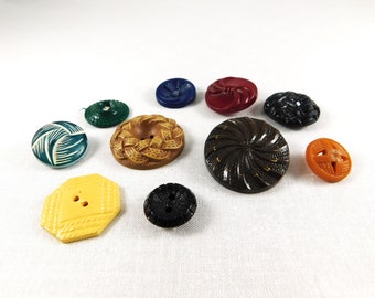 May include: Assortment of vintage buttons in various colors and designs, including green, blue, red, brown, yellow, and orange. The buttons are made of plastic and have different textures and patterns.