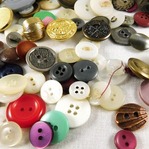 May include: A collection of assorted buttons in various colors, shapes, and sizes. The buttons are made of different materials, including metal, plastic, and fabric. Some buttons have a decorative design, while others are plain.