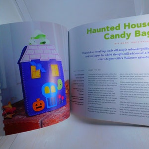 May include: A craft project for a haunted house candy bag. The bag is made of felt and features a purple house with a skull, pumpkin, and bat appliques. The instructions are written in a book.