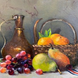 Puede incluir: Naturaleza muerta de frutas y una jarra de cobre. Una cesta de mimbre contiene naranjas con hojas verdes. También hay uvas, peras y una cinta roja y azul. El fondo es de un gris apagado.