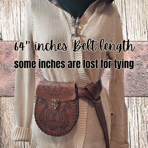 May include: A brown leather belt with a decorative buckle and a matching brown leather bag with a Celtic knot design. The belt is 64 inches long, and some inches are lost for tying.