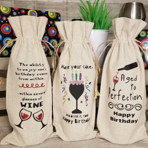 May include: Three beige linen wine bottle gift bags with different birthday sayings. The first bag says "The ability to enjoy one's birthday comes from within... within several glasses of WINE". The second bag says "Have your cake. And drink it too! Happy Birthday". The third bag says "Aged to perfection. Happy Birthday".