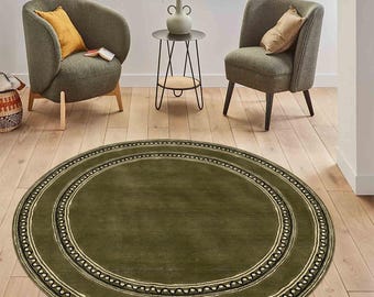 May include: A round, green area rug with a double border of black and white geometric patterns. The rug is in a living room setting with two green armchairs and a black metal side table.
