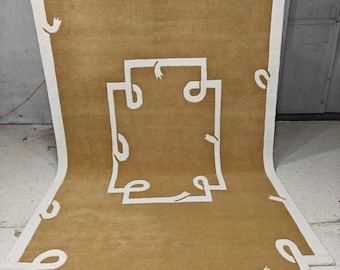 May include: A large, rectangular rug with a white border and a brown center. The rug has a white design of interlocking loops throughout the center.