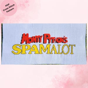 Könnte beinhalten: Ein Kreuzstichmuster mit den Worten "Monty Python's SPAMALOT" in Rot und Gelb auf hellblauem Hintergrund. Die Wörter sind in einer kräftigen, verspielten Schriftart gestickt. Ein rosa Kreis mit dem Text "PDF Cross Stitch Pattern" befindet sich in der oberen linken Ecke.