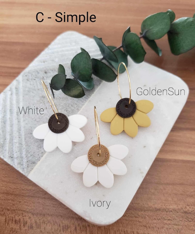 May include: Three pairs of gold hoop earrings with a flower charm. The flowers are white, ivory, and yellow. The text "C - Simple" is at the top of the image. The text "White", "GoldenSun", and "Ivory" are below the earrings.