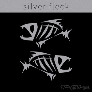 May include: Two silver fish skeletons with a textured, metallic finish on a black background. The text "silver fleck" appears above the fish. The text "Outer City Designs" appears below the fish.