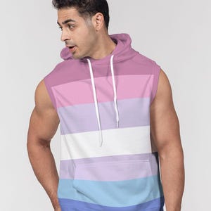 Puede incluir: Sudadera sin mangas con diseño de bloques de color en tonos rosa, morado, blanco, azul claro y azul. La sudadera con capucha tiene un cordón y un bolsillo delantero. La prenda está hecha de un material suave.
