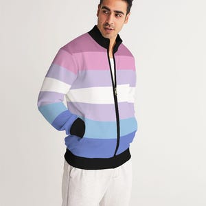May include: A black zip-up jacket with a horizontal striped pattern in shades of pink, purple, blue, and white. The jacket has a stand-up collar and two pockets.