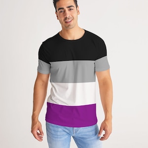 Könnte beinhalten: Ein schwarz-grau-weiß-violettes gestreiftes T-Shirt. Das Shirt hat einen Rundhalsausschnitt und kurze Ärmel.