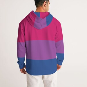 May include: A pink, purple, and blue striped hoodie with a drawstring hood. The hoodie is made of a soft, comfortable material and has a relaxed fit.