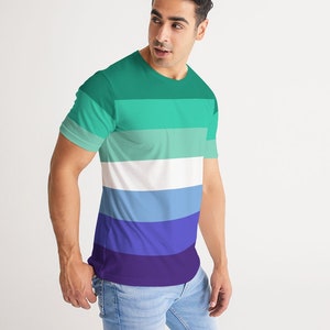 Puede incluir: Una camiseta de manga corta con un patr&oacute;n de rayas horizontales en tonos de verde, azul y morado. La camiseta tiene cuello redondo y un ajuste holgado.