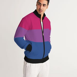 May include: A black zippered jacket with a horizontal stripe pattern in pink, purple, and blue. The jacket has a stand-up collar and two pockets.