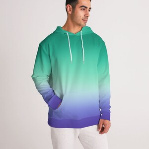May include: A green and purple ombre hoodie with a drawstring hood. The hoodie has a kangaroo pocket and a ribbed hem.