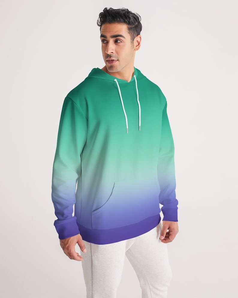 May include: A green and purple ombre hoodie with a drawstring hood and a kangaroo pocket. The hoodie has a relaxed fit and a long length.