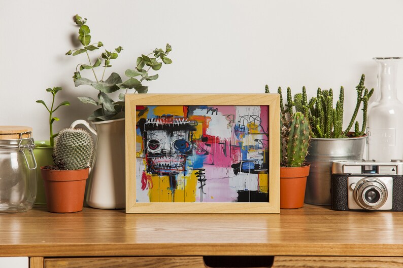 Puede incluir: Una impresi&oacute;n enmarcada de una pintura abstracta colorida con una cara de calavera en el centro. La pintura est&aacute; en un marco de madera claro y est&aacute; sentada sobre una mesa de madera con plantas y una c&aacute;mara.