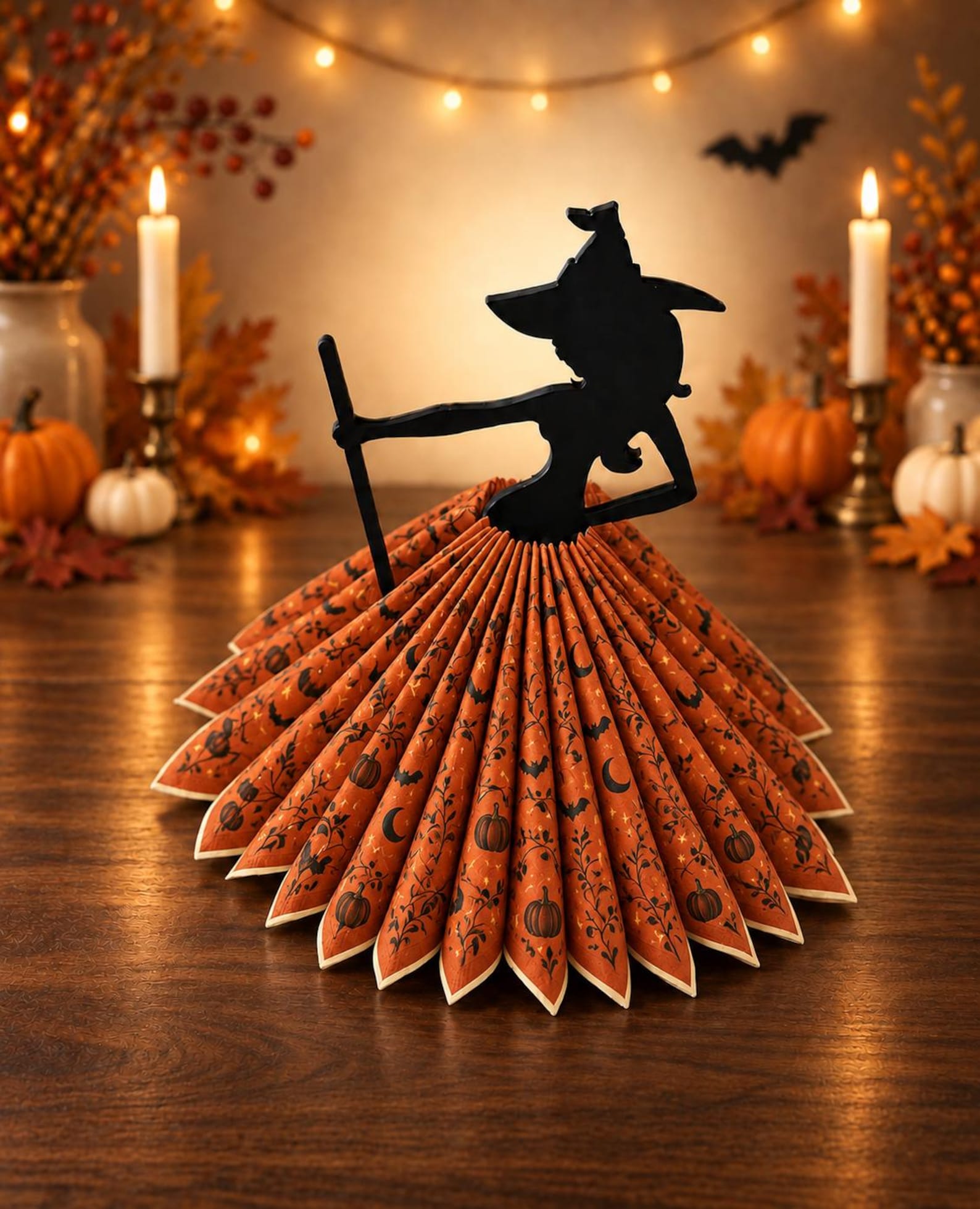A Witch Holder with a Fan-Shaped Skirt Witch-shaped napkin holder displaying a wide fan of orange napkins as a skirt.