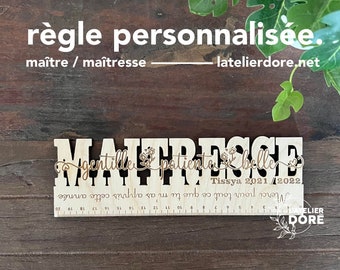 Puede incluir: Una regla de madera con la palabra "MAITRESSE" grabada en ella. La regla está decorada con pequeñas flores y las palabras "gentille", "patiente" y "belle". La regla también incluye el texto "Tissya 2021/2022" y "Merci pour tout ce que tu m'as appris cette année".