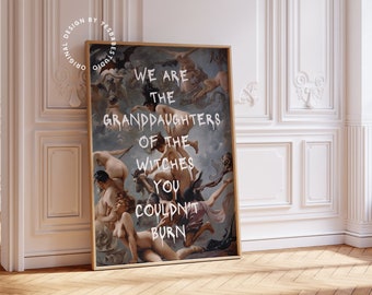 May include: A framed art print with the text "WE ARE THE GRANDDAUGHTERS OF THE WITCHES YOU COULDN'T BURN" in white lettering. The artwork features a classical painting style with figures and a muted color palette. The frame is a light brown color.