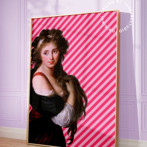 May include: A framed print of a woman with long brown hair wearing a white and black dress against a pink and white striped background. The text "ORIGINAL DESIGN BY YES BABE STUDIO" is printed in a circle around the frame.