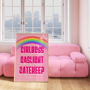 Pu&ograve; includere: Stampa incorniciata rosa e oro con un arcobaleno e il testo "Girlboss Gaslight Gatekeep" in rosa.