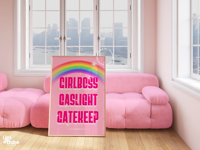 Pu&ograve; includere: Stampa incorniciata rosa e oro con un arcobaleno e il testo "Girlboss Gaslight Gatekeep" in rosa.
