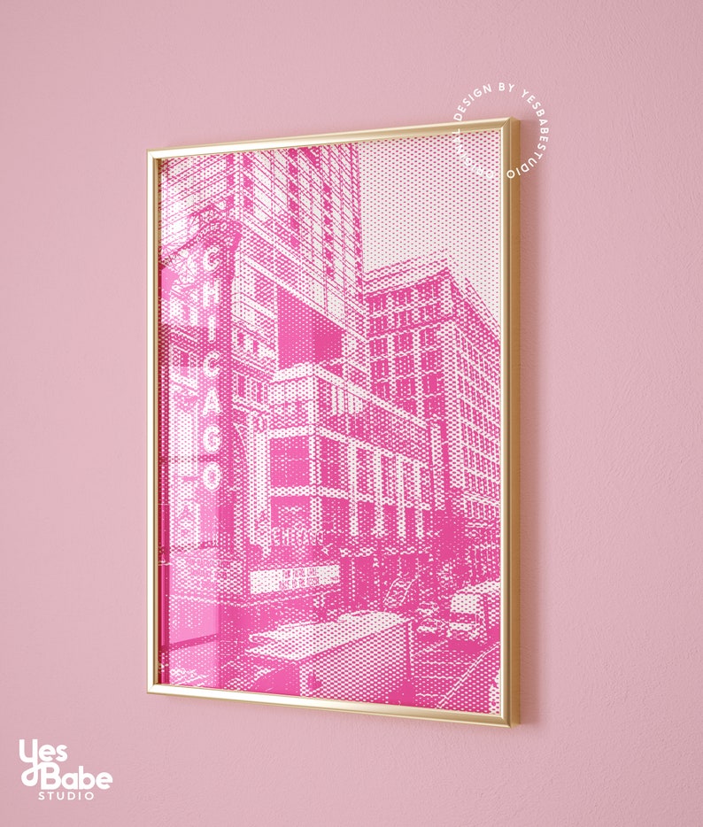Op de afbeelding: Een ingelijste roze en witte prent van een Chicago stadsgezicht. Het kunstwerk heeft een halftone stippenpatroon en het woord "CHICAGO" in grote letters. De lijst is goudkleurig en de achtergrond is effen roze.