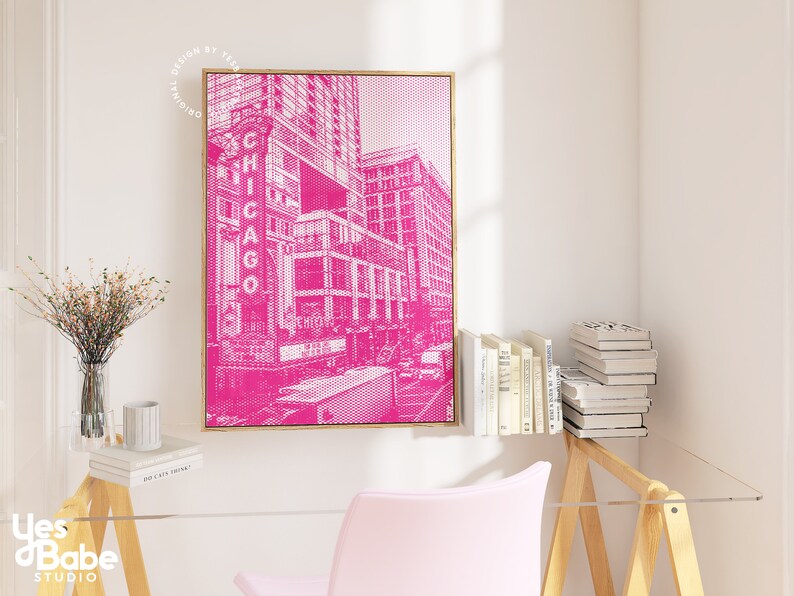 Op de afbeelding: Een ingelijste roze en witte prent van een Chicago stadsgezicht. Het kunstwerk heeft een halftone stippenpatroon en het woord "CHICAGO" in grote letters. De prent wordt weergegeven in een gouden lijst en hangt aan een witte muur.