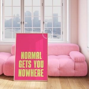 May include: A pink framed poster with the text "NORMAL GETS YOU NOWHERE" in yellow on a pink background.