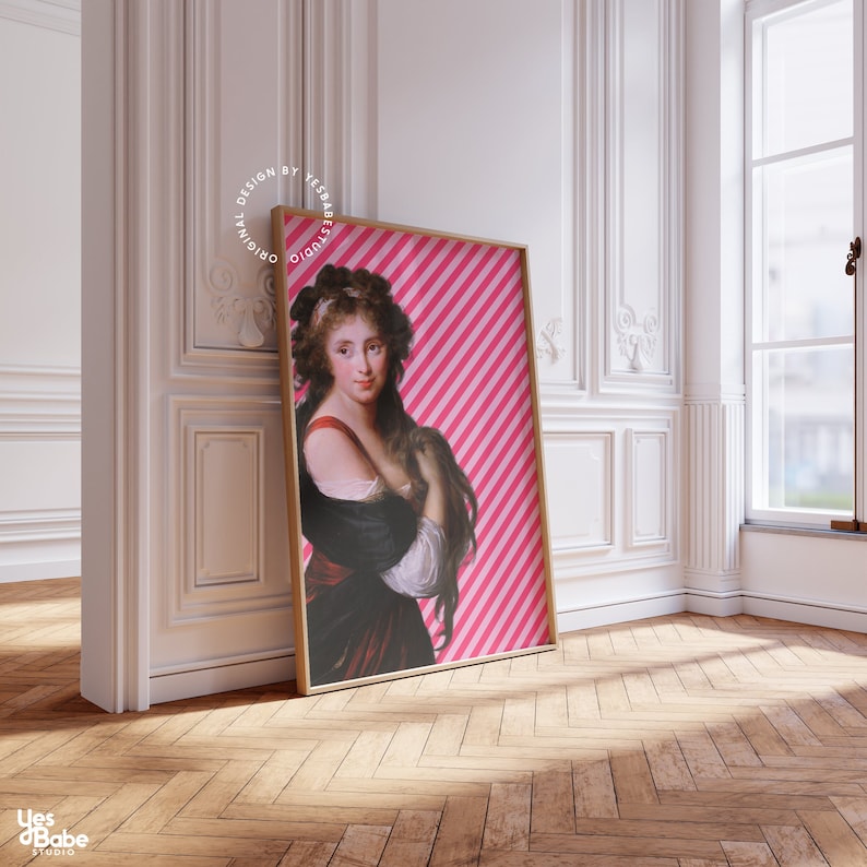 May include: A framed print of a woman with long dark hair wearing a black dress with a red sash. The background is a pink and white striped pattern. The frame is a light wood color.