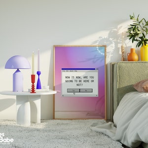 Pu&ograve; includere: Una stampa incorniciata con uno sfondo sfumato di rosa, viola e blu. La stampa presenta uno schermo del computer con una finestra pop-up che dice "NOW IS NOW, ARE YOU GOING TO BE HERE OR NOT?" con pulsanti che dicono "S&igrave;" e "No".