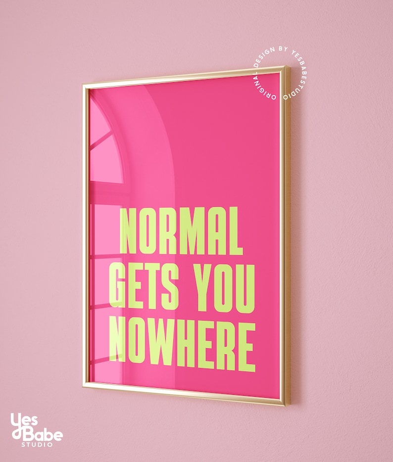 May include: A framed pink poster with gold trim. The poster has the text "NORMAL GETS YOU NOWHERE" in yellow.