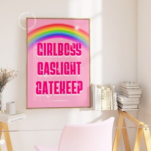 Pu&ograve; includere: Poster rosa e bianco con un arcobaleno e il testo "Girlboss Gaslight Gatekeep" in rosa.