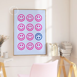 Pu&ograve; includere: Una stampa incorniciata con sfondo blu e una griglia di 15 facce sorridenti rosa e blu. Una delle facce sorridenti &egrave; capovolta.