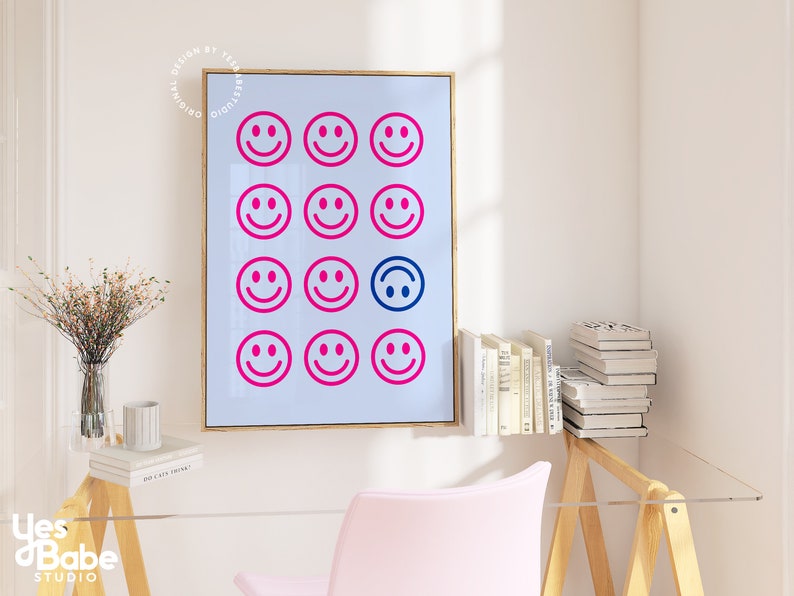 Pu&ograve; includere: Una stampa incorniciata con sfondo blu e una griglia di 15 facce sorridenti rosa e blu. Una delle facce sorridenti &egrave; capovolta.