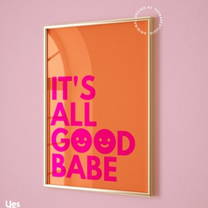 May include: A framed art print with an orange background and the text "IT'S ALL GOOD BABE" in bright pink. The print includes two smiling face emojis. The frame is gold, and the background is a light pink.