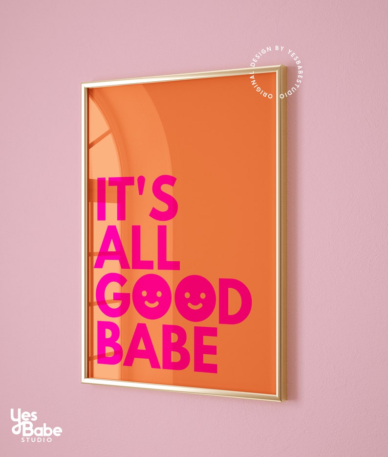 May include: A framed art print with an orange background and the text "IT'S ALL GOOD BABE" in bright pink. The print includes two smiling face emojis. The frame is gold, and the background is a light pink.