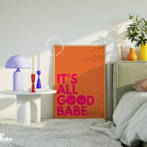 May include: An orange poster with the text "IT'S ALL GOOD BABE" in pink, a white table with a purple lamp, and two candlesticks. A bed with a green headboard and a yellow vase are also visible.
