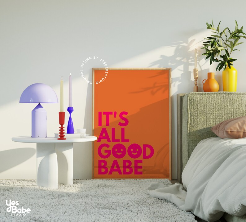 May include: An orange poster with the text "IT'S ALL GOOD BABE" in pink, a white table with a purple lamp, and two candlesticks. A bed with a green headboard and a yellow vase are also visible.