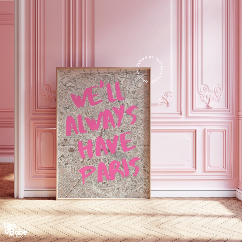 K&ouml;nnte beinhalten: Ein rosa und wei&szlig; gerahmter Druck mit einer Vintage-Karte von Paris als Hintergrund. Der Text "We'll Always Have Paris" ist in rosa &uuml;ber die Karte geschrieben.